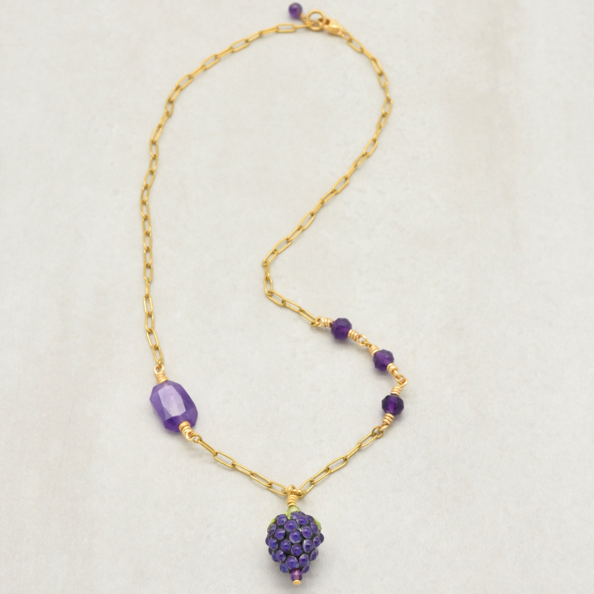 Asymmetrical gold chain necklace with artisan lampwork glass blackberry focal and amethyst on a light background - handmade with love by Ruby Acorn