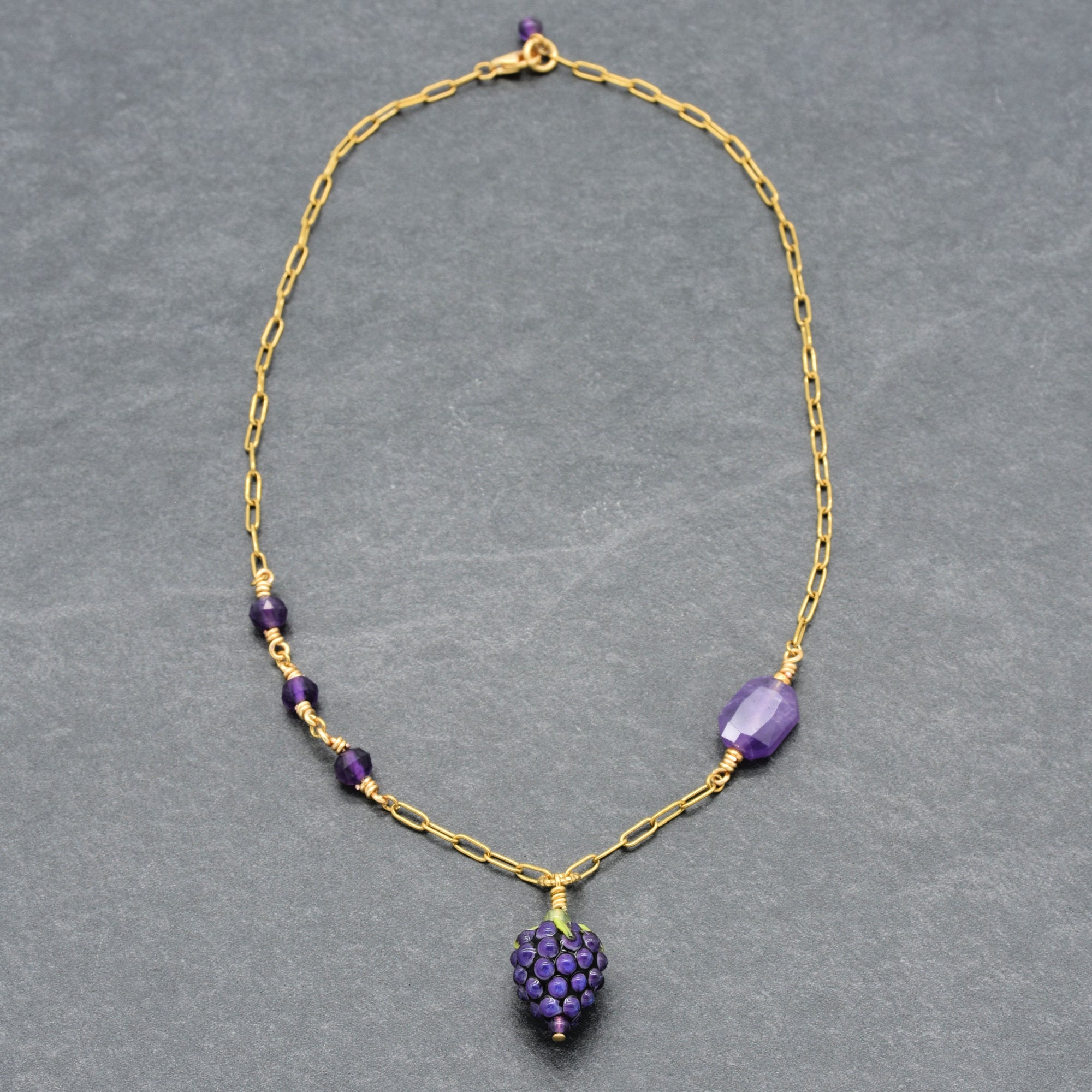 Asymmetrical gold chain necklace with artisan lampwork glass blackberry focal and amethyst on a gray background - handmade with love by Ruby Acorn