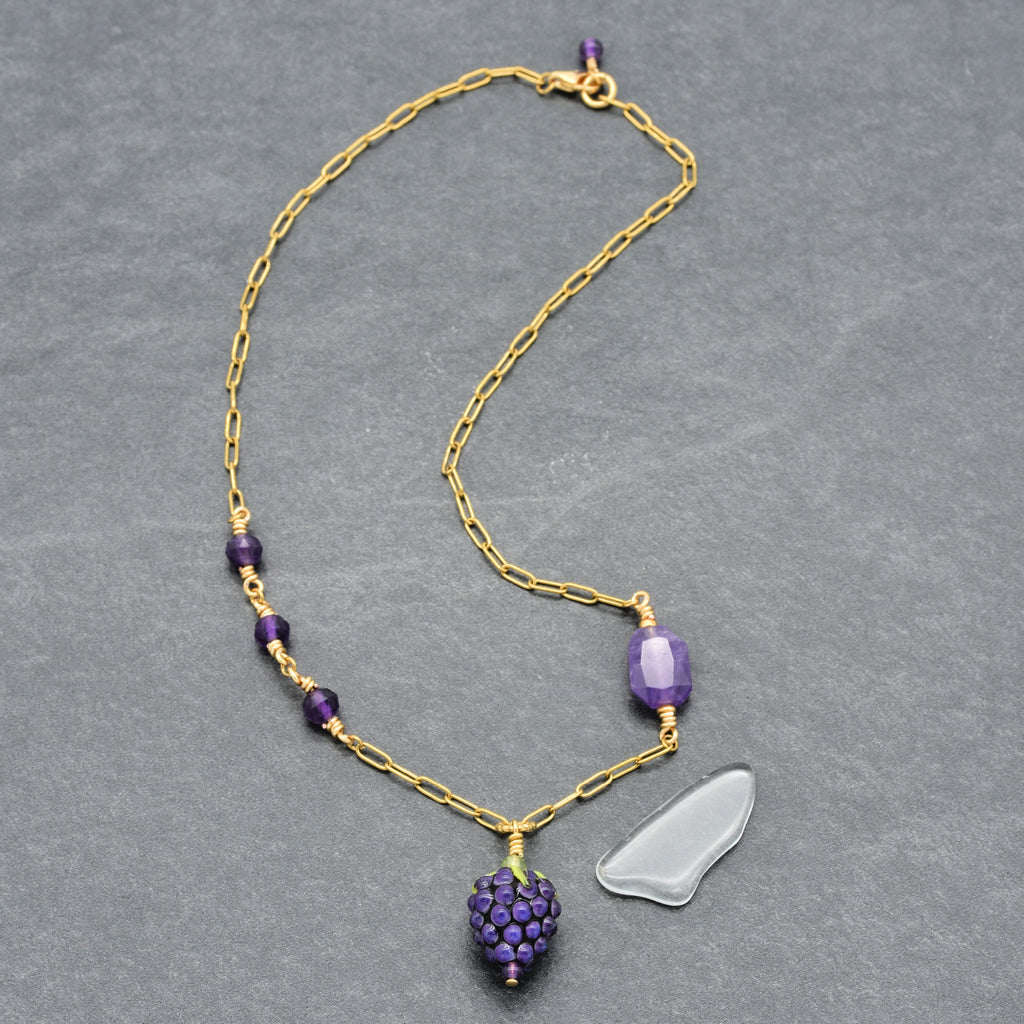 Asymmetrical gold chain necklace with artisan lampwork glass blackberry focal and amethyst on a gray background - handmade with love by Ruby Acorn