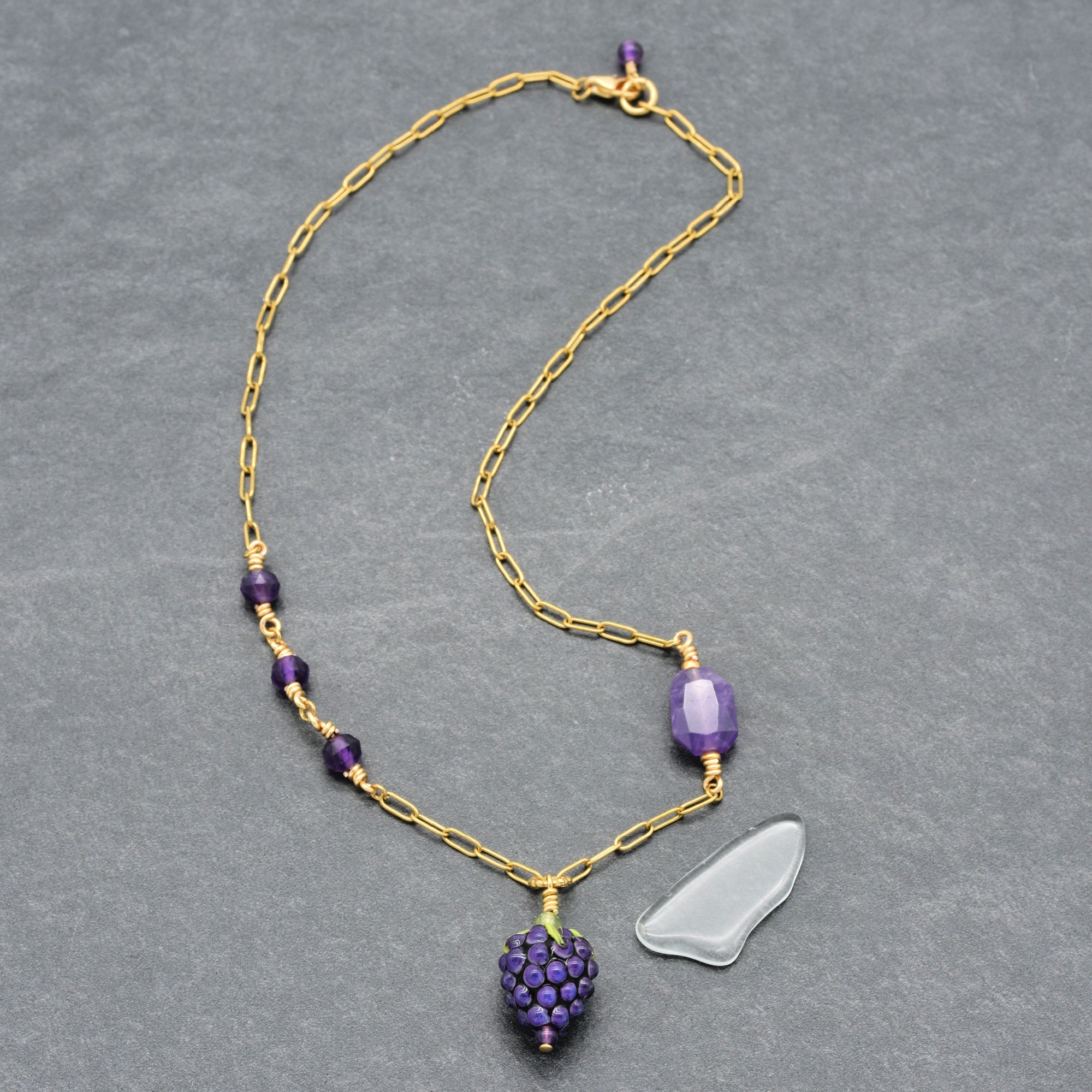 Asymmetrical gold chain necklace with artisan lampwork glass blackberry focal and amethyst on a gray background - handmade with love by Ruby Acorn
