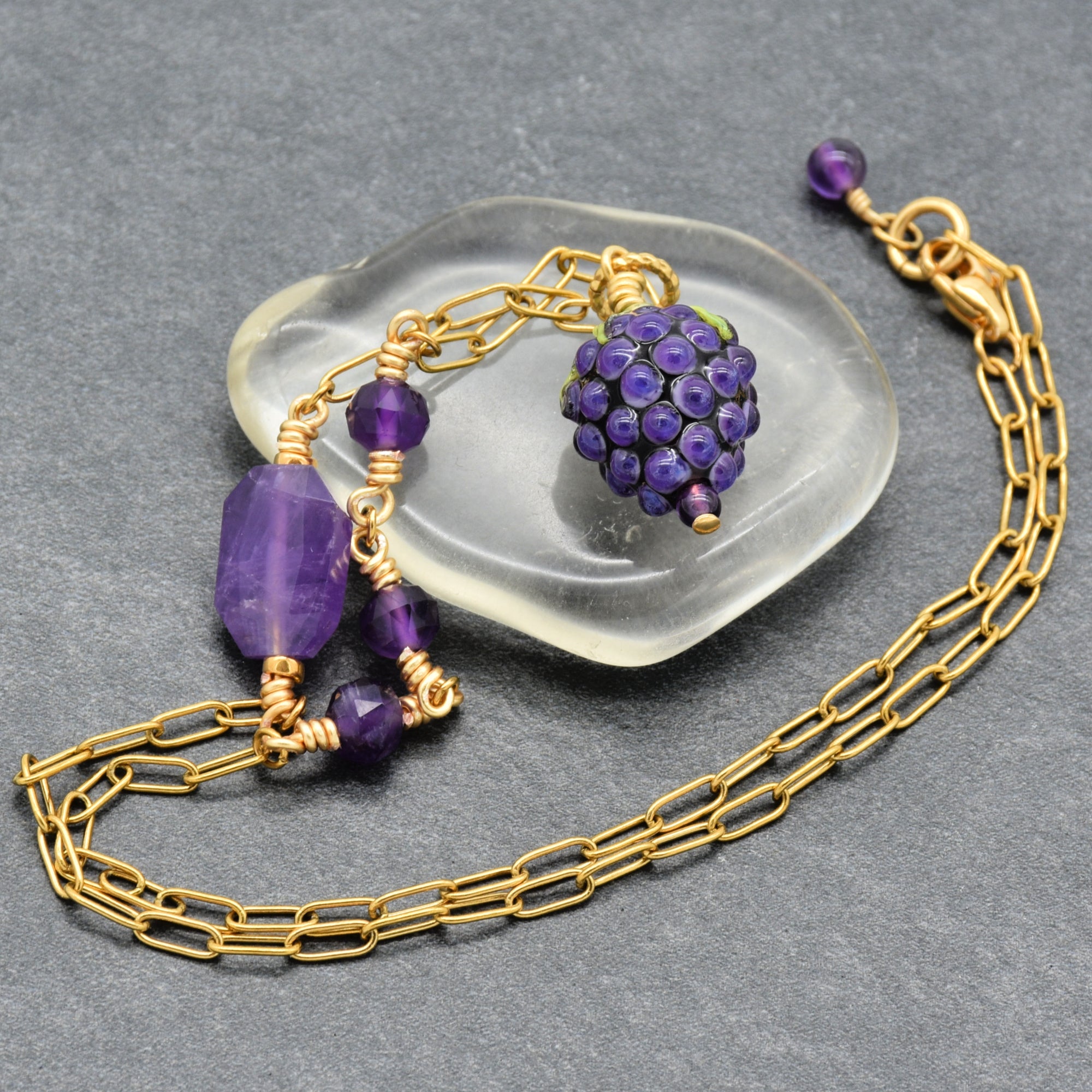 Asymmetrical gold chain necklace with artisan lampwork glass blackberry focal and amethyst on a gray background - handmade with love by Ruby Acorn