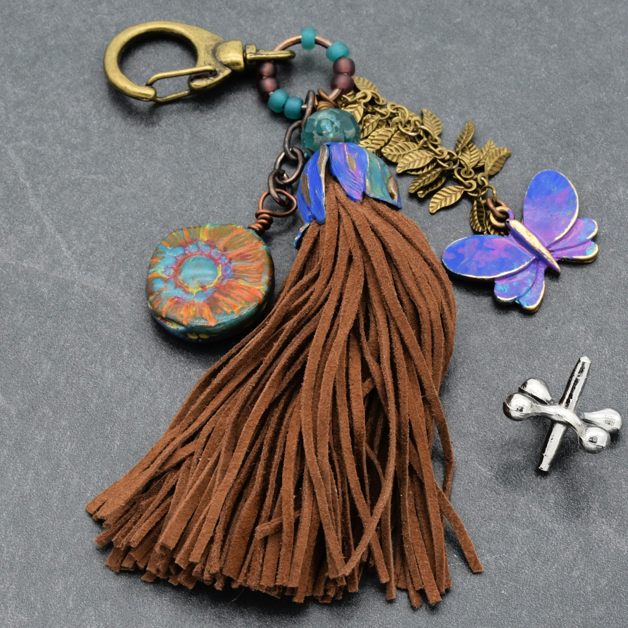 Keychain with tassel, butterfly charm, and decorative elements on a gray background