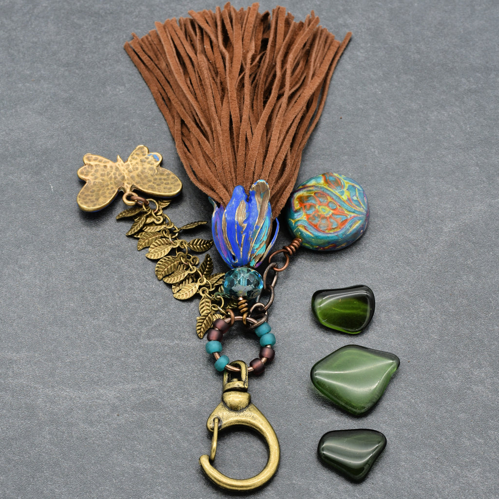 Decorative keychain with tassel, beads, and stones on a gray background