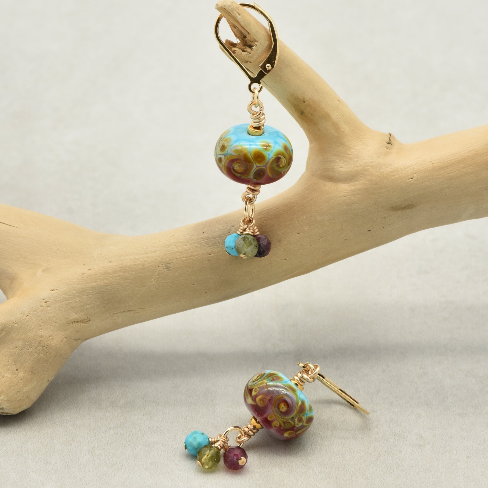 Colorful lampwork earrings displayed on a branch