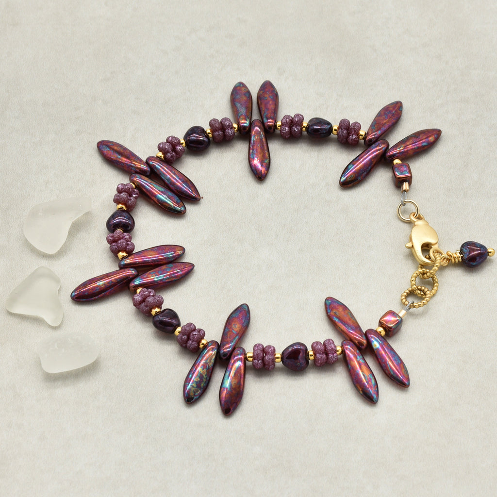 Bracelet with burgundy and gold beads on a light gray background