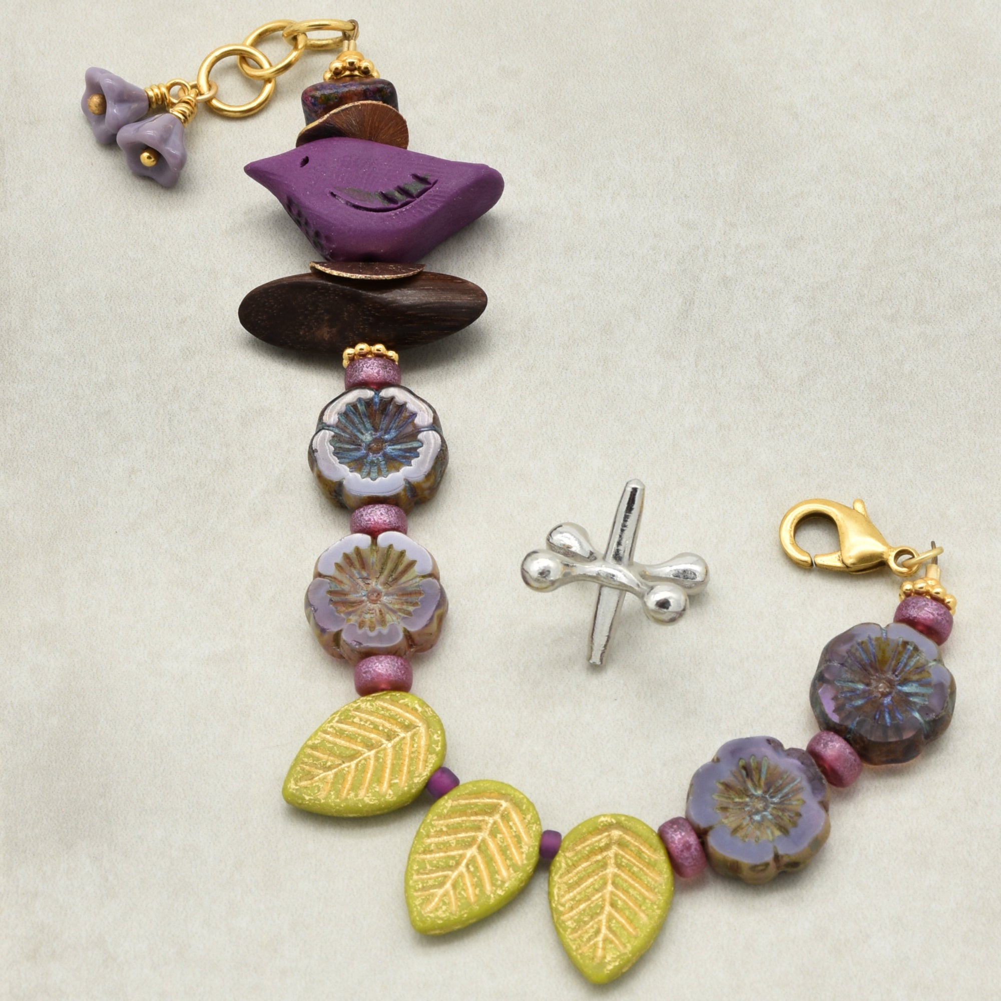 Colorful beaded bracelet with various charms on a light background