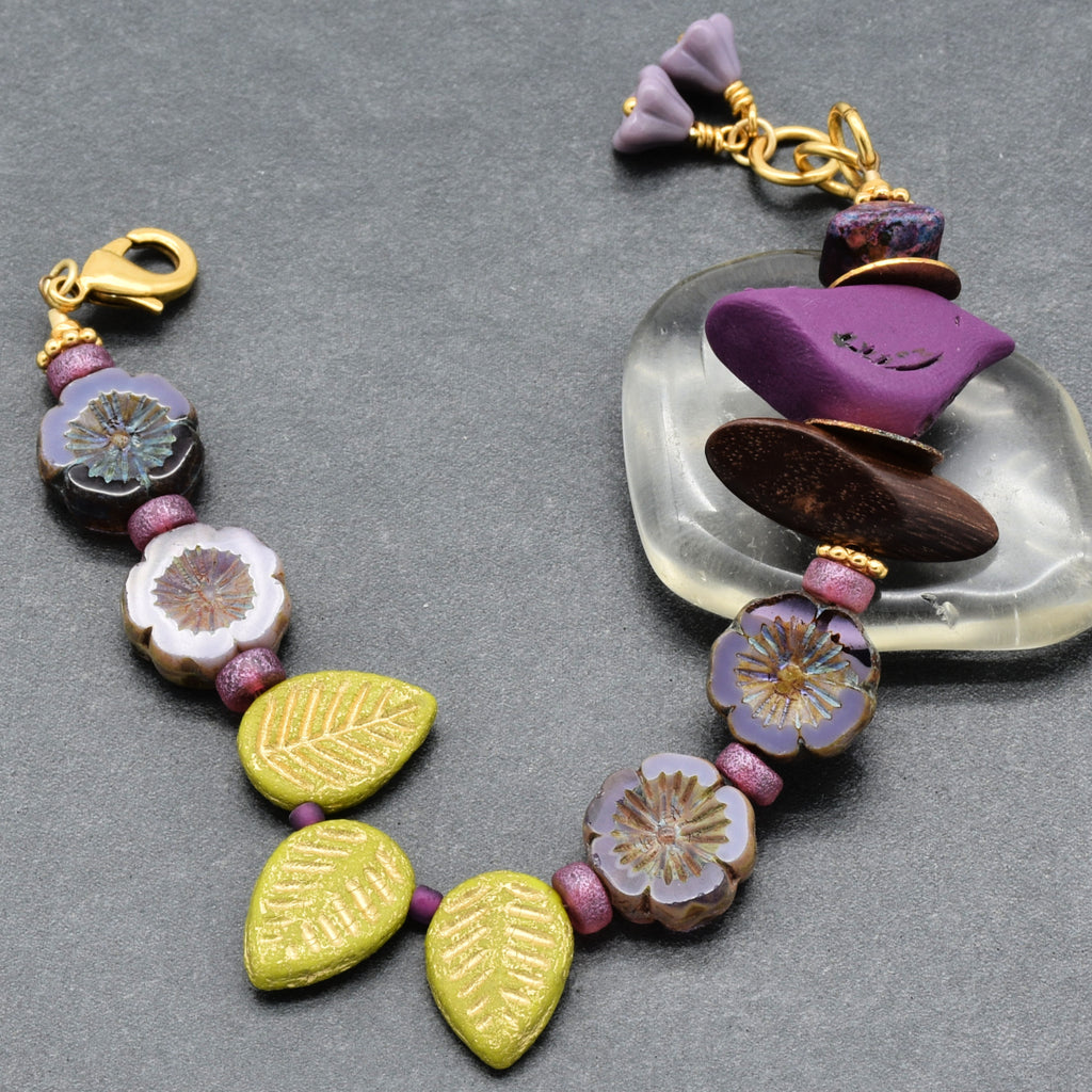 Colorful beaded bracelet with floral and leaf designs on a gray background