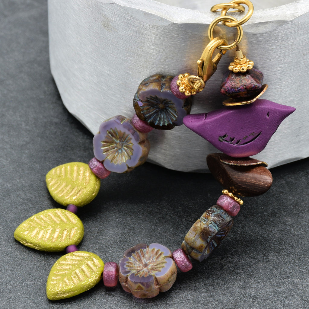 Colorful beaded bracelet with a bird focal on a gray surface