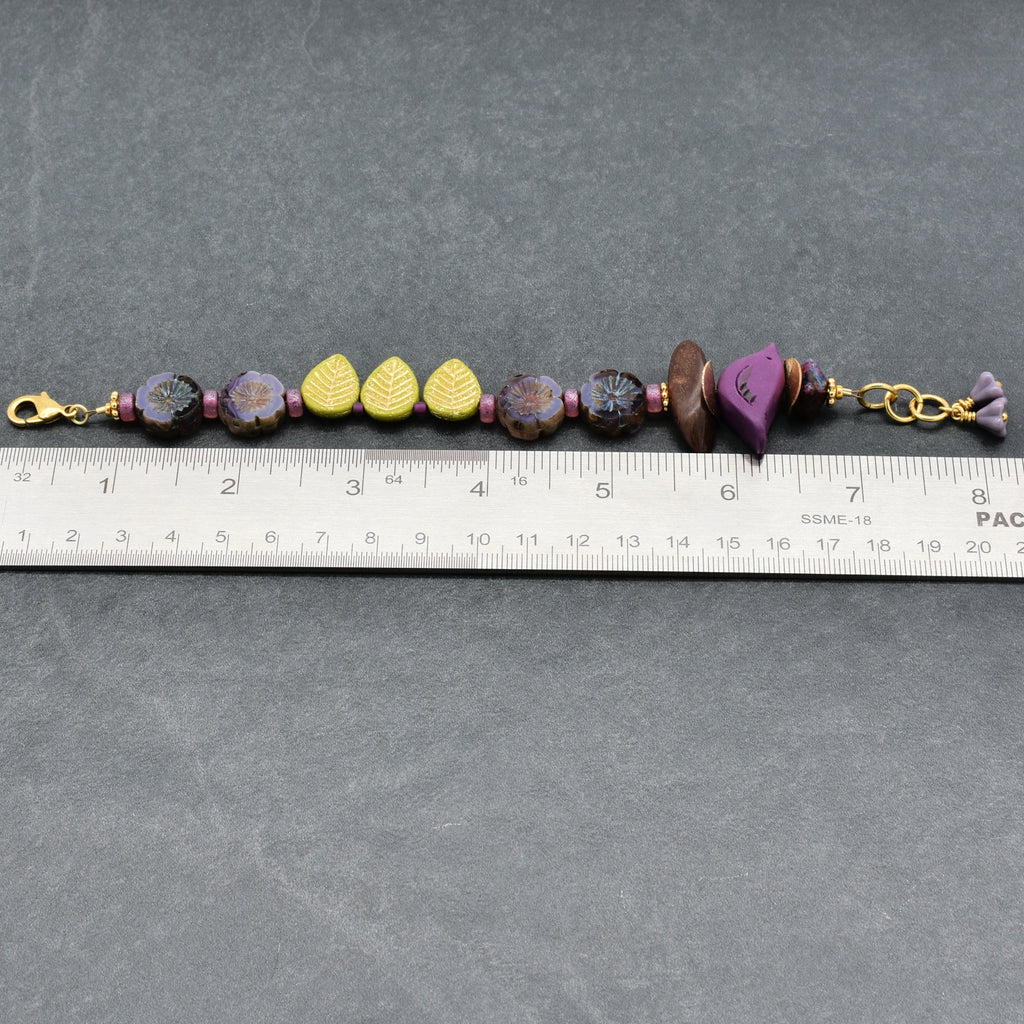 Beaded bracelet with gold clasps on a gray surface with a ruler for scale.