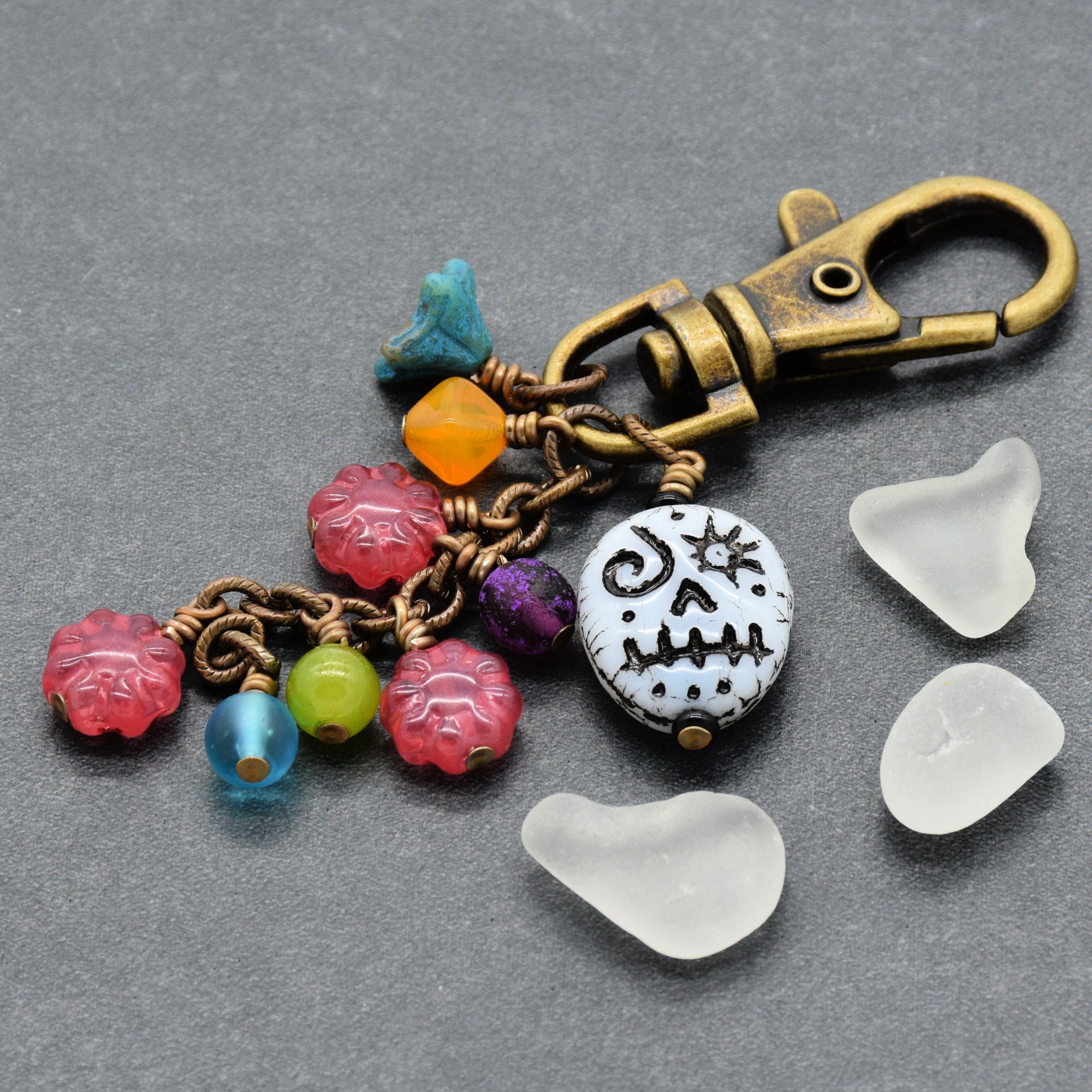 Colorful beaded keychain with a skull charm on a gray surface