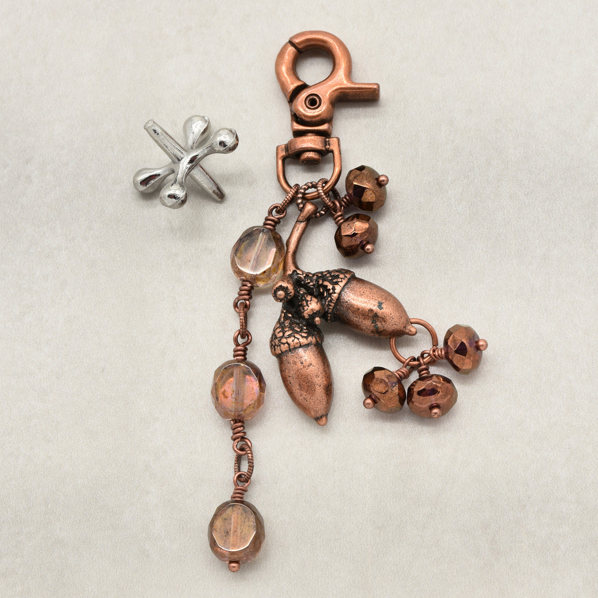 The Acorn Keeper Handbag Charm featuring a rare antique copper acorn focal with light topaz Czech glass charms, handmade by Ruby Acorn