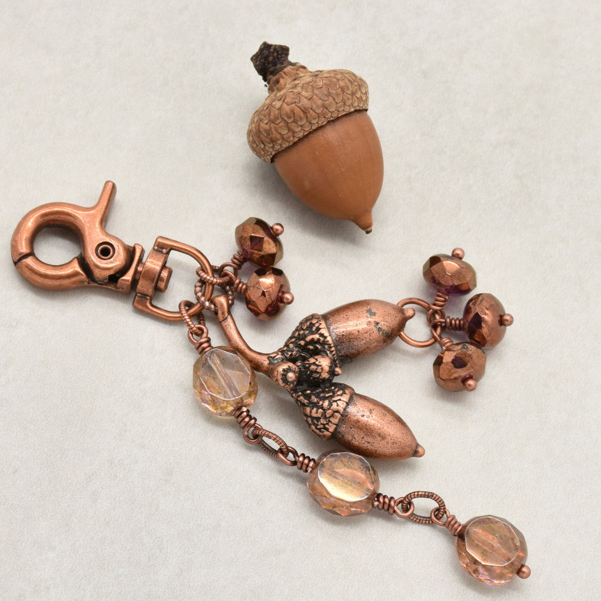The Acorn Keeper Handbag Charm featuring a rare antique copper acorn focal with light topaz Czech glass charms, handmade by Ruby Acorn