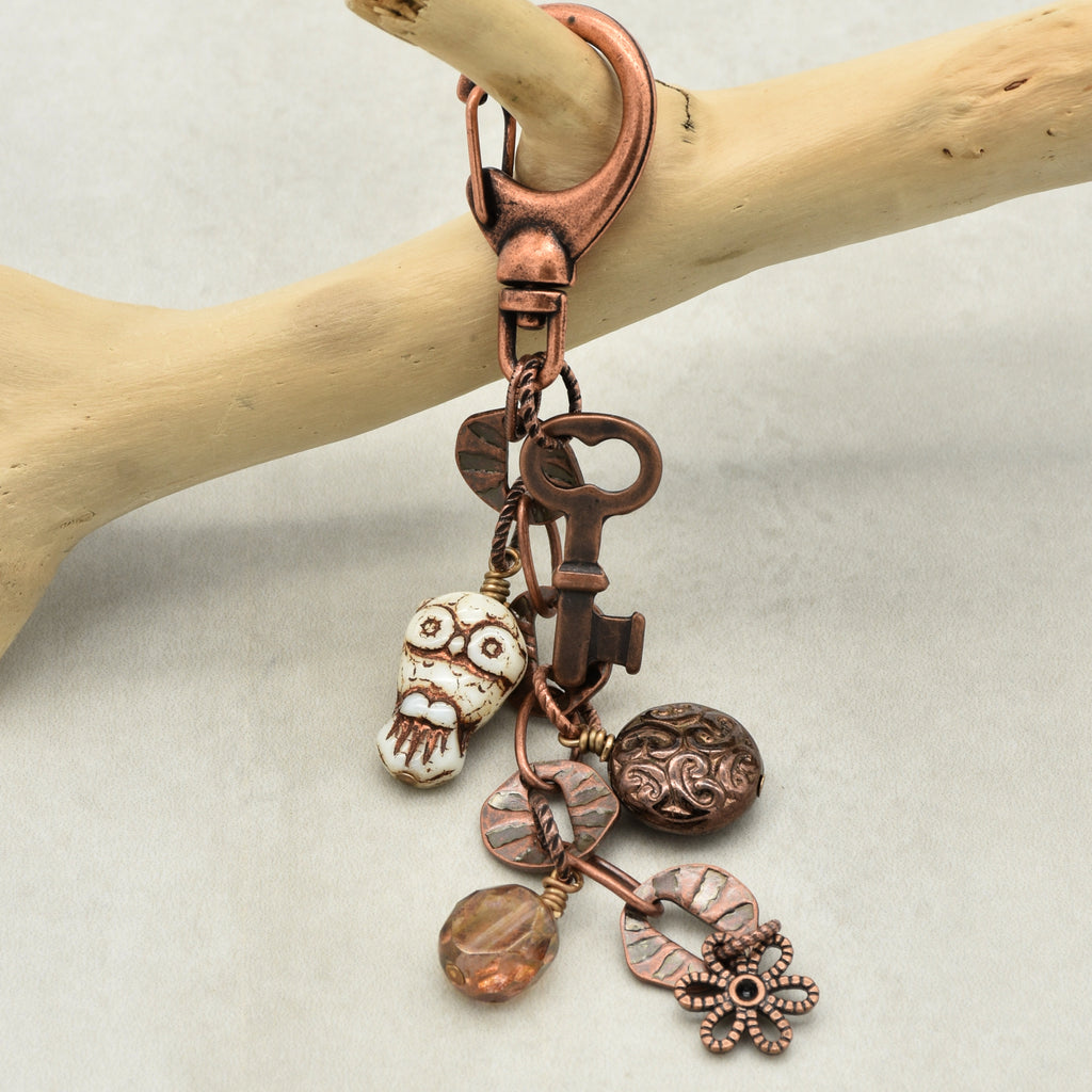Copper keychain with various charms on a wooden branch