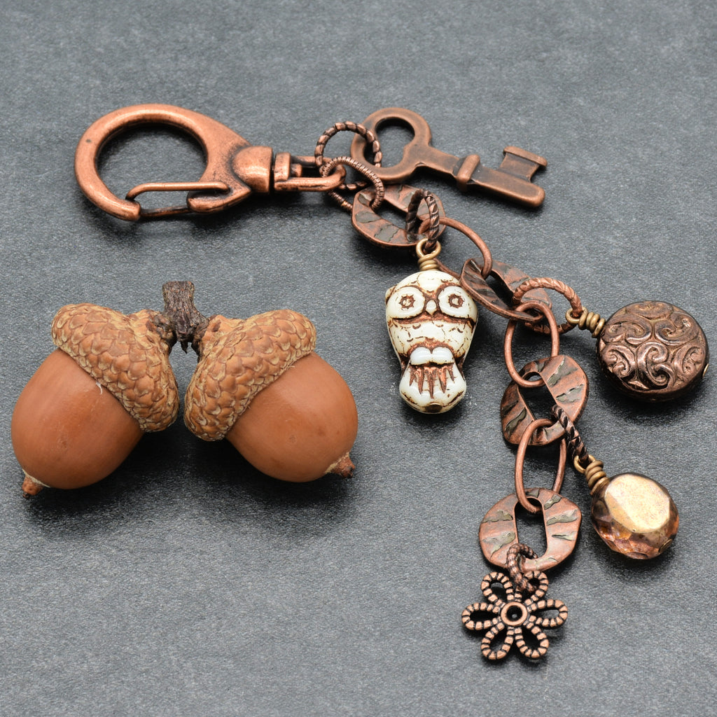 Copper keychain with charms and decorative elements on a gray background