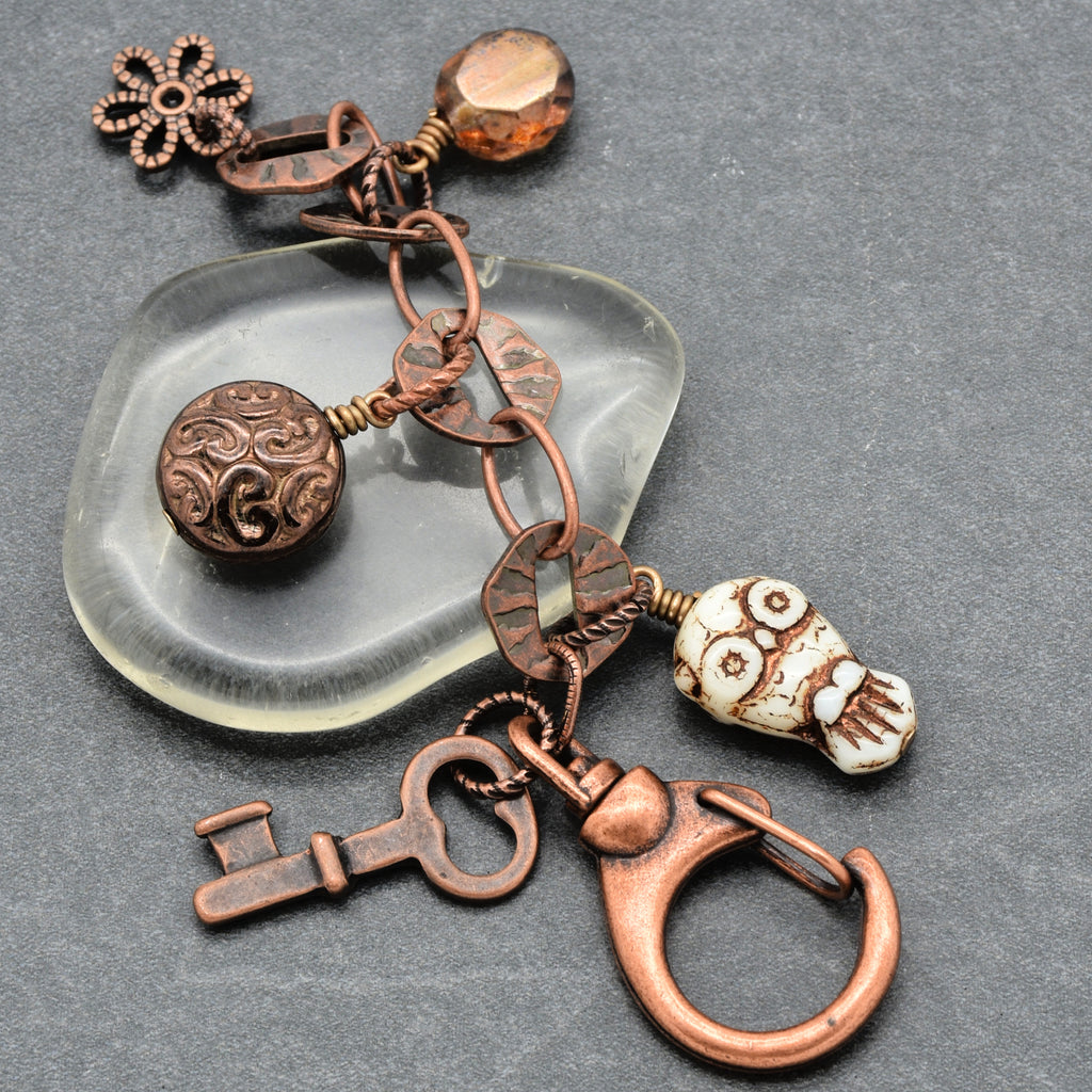 Copper keychain with decorative elements on a gray background