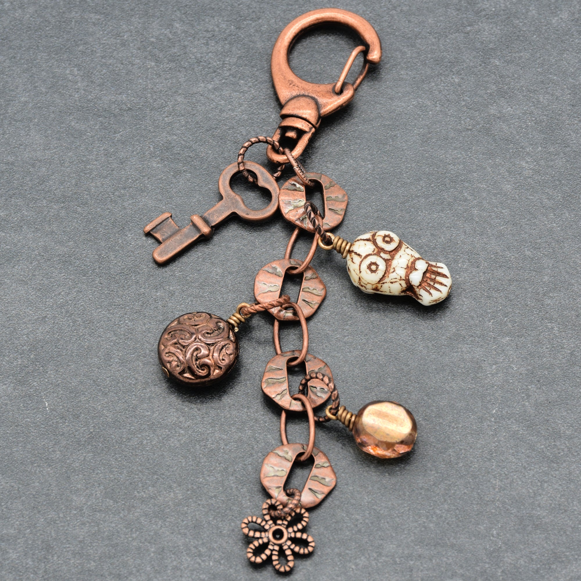 Copper keychain with various charms on a gray background