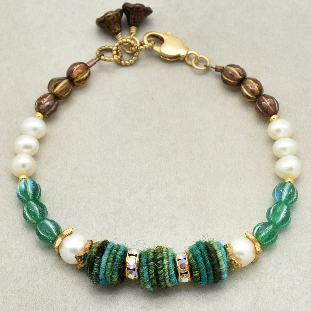 Bracelet with pearls and green and brown beads on a light gray background