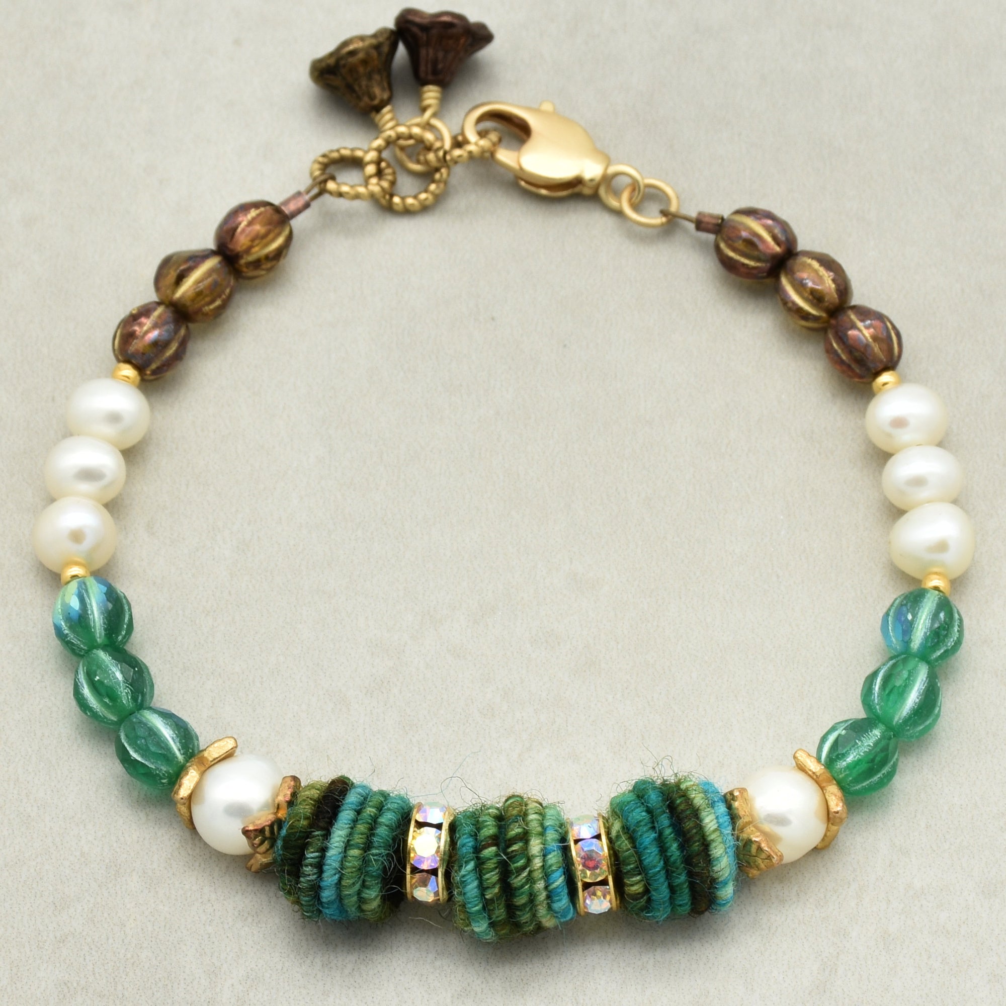 Bracelet with pearls and green and brown beads on a light gray background