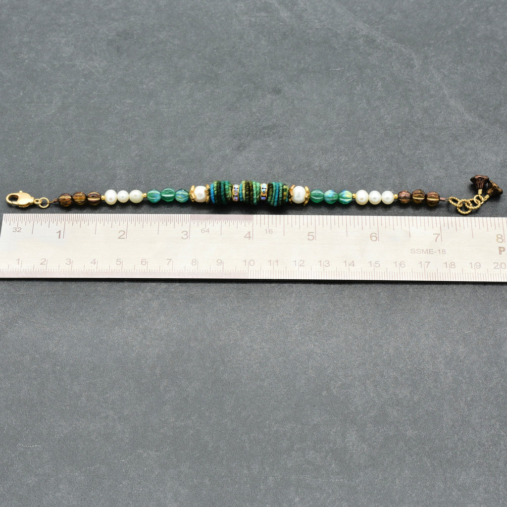Beaded bracelet with a ruler for size reference on a gray background