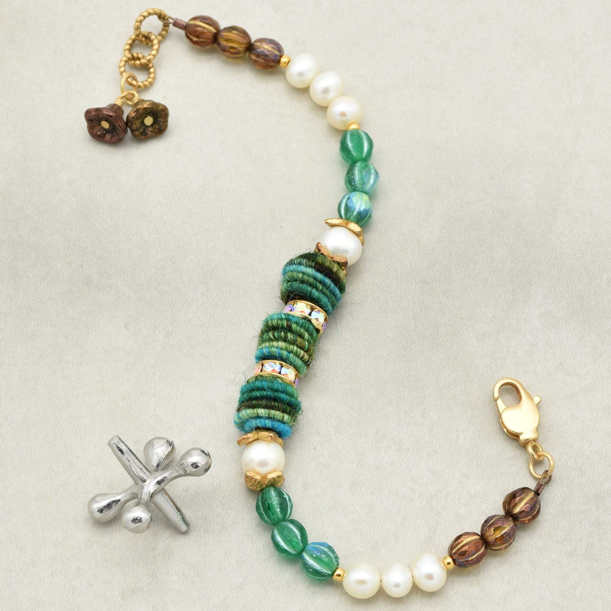 Beaded bracelet with green, brown, and white beads on a light gray background
