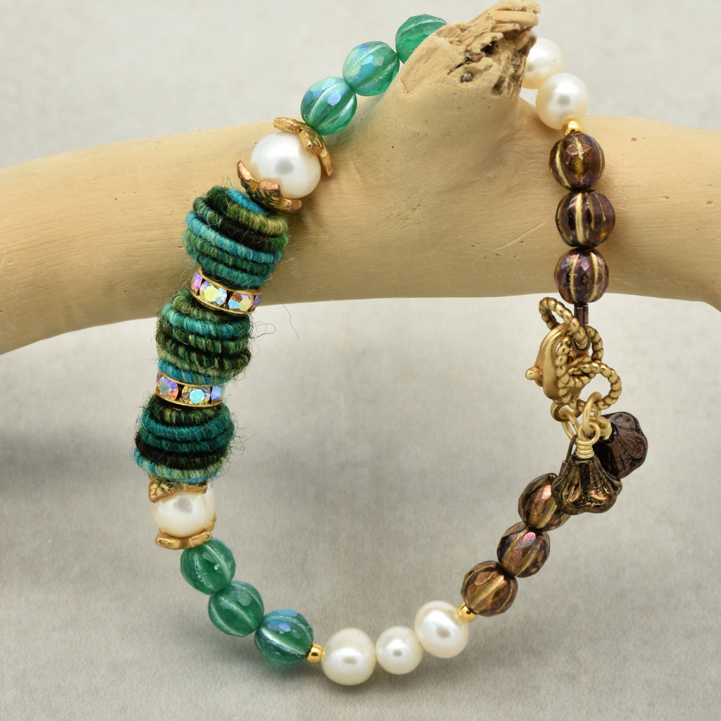 Beaded bracelet on a wooden branch against a neutral background