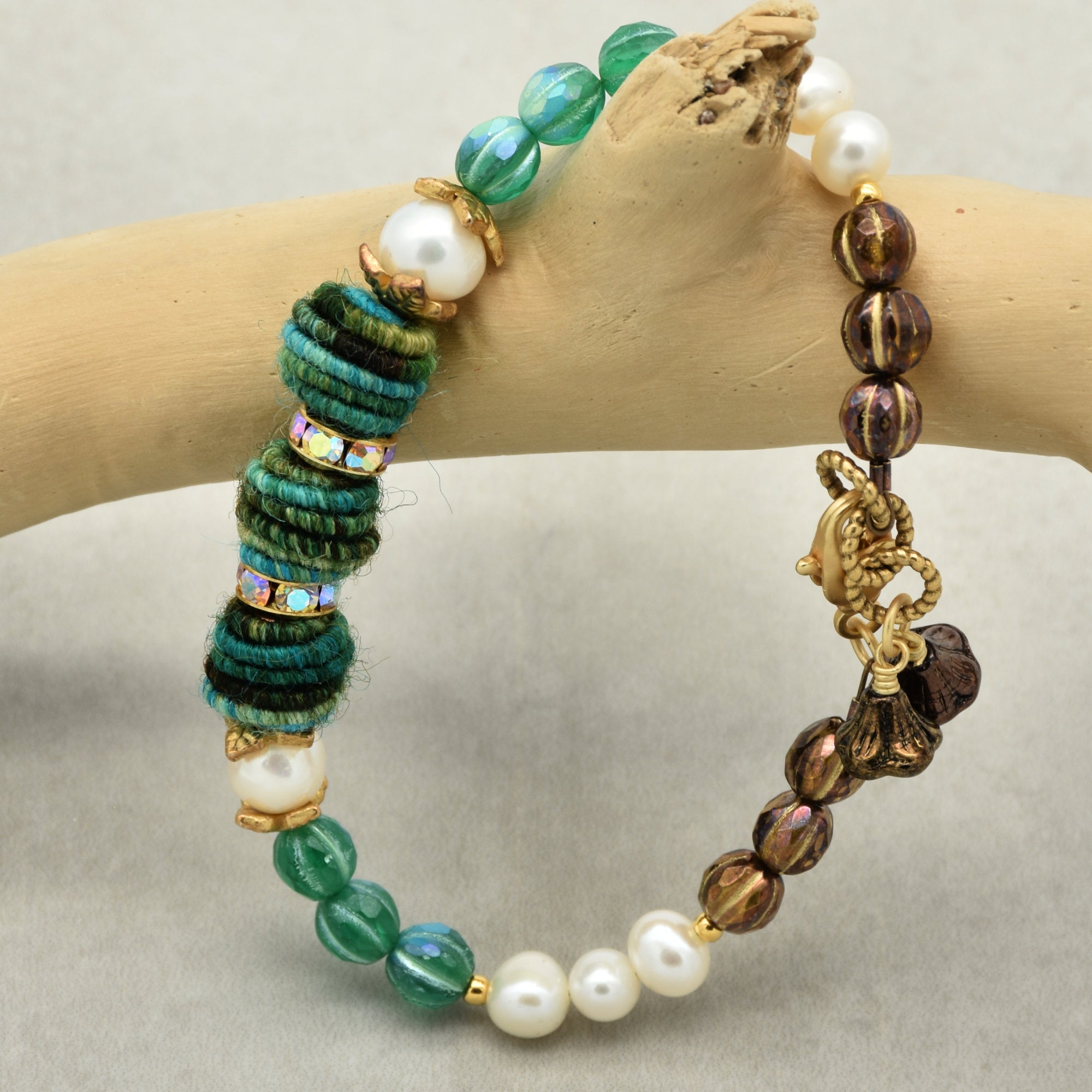 Beaded bracelet on a wooden branch against a neutral background