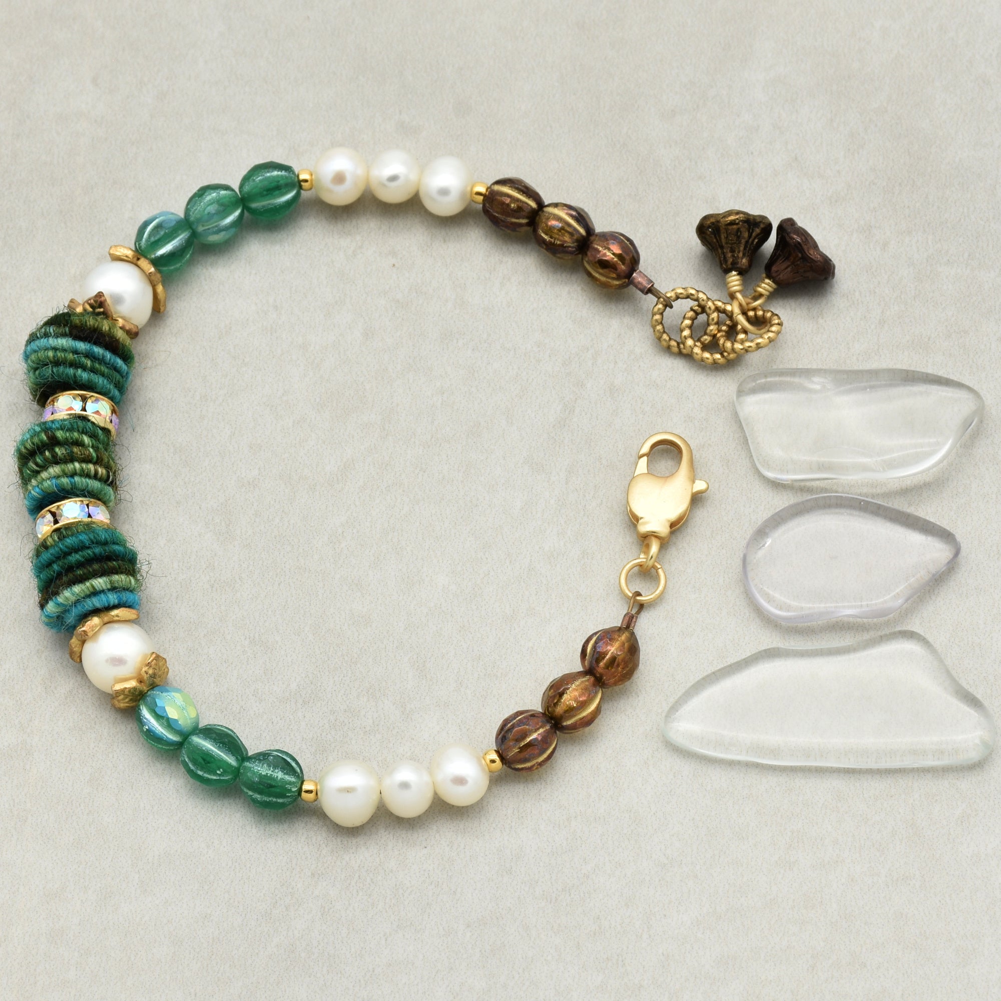 Beaded bracelet with green, brown, and white beads on a light gray background