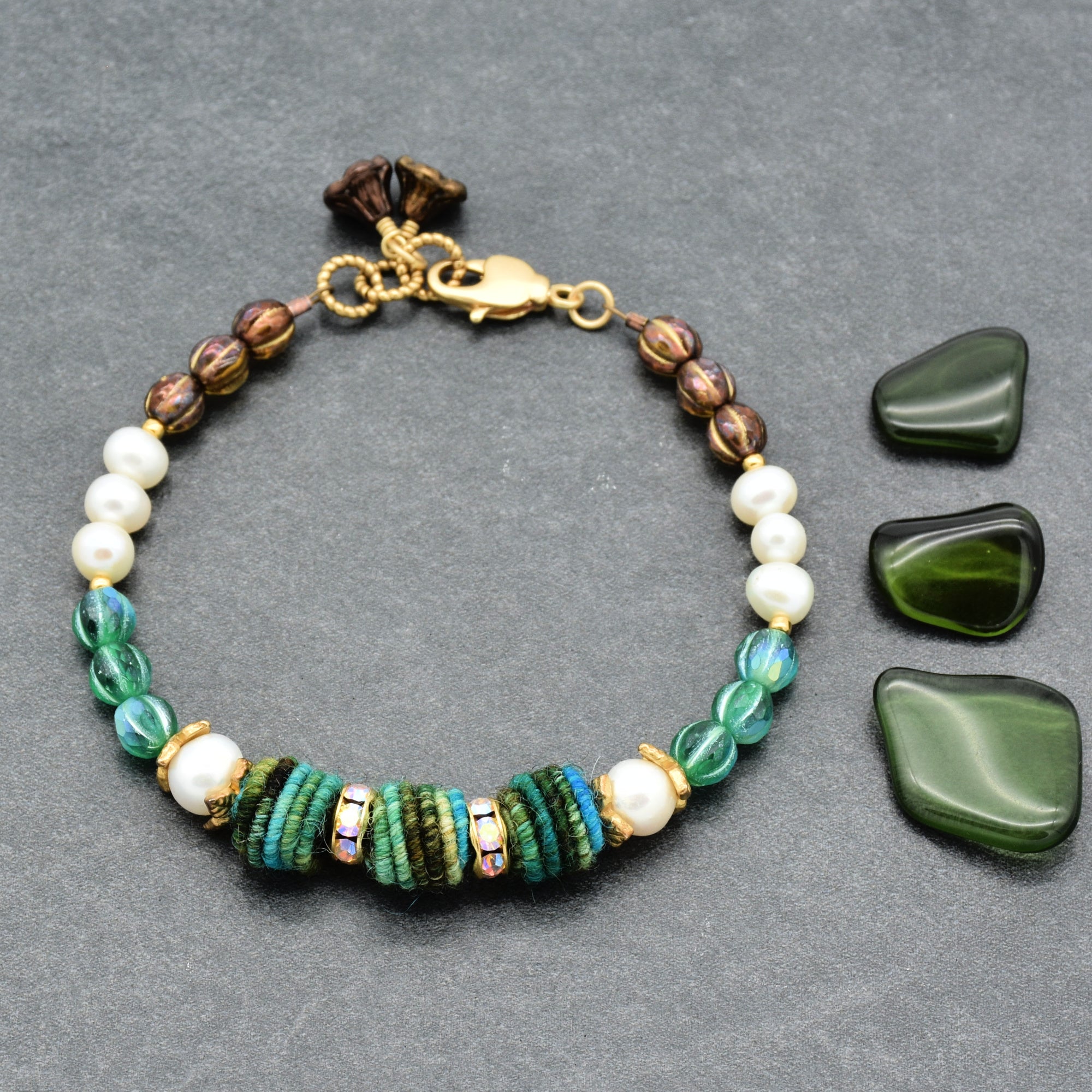 Beaded bracelet with green and white stones on a gray background