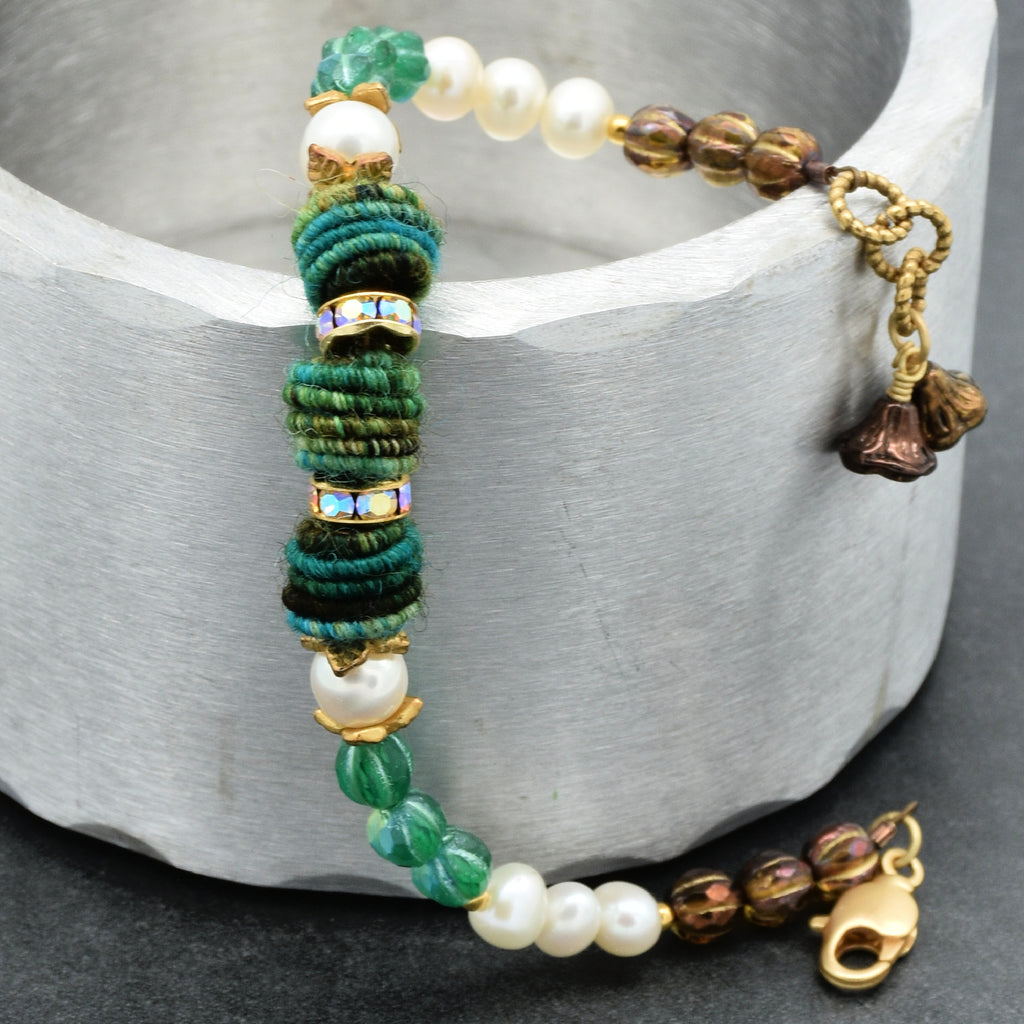 Beaded bracelet with green, white, and gold beads on a gray surface