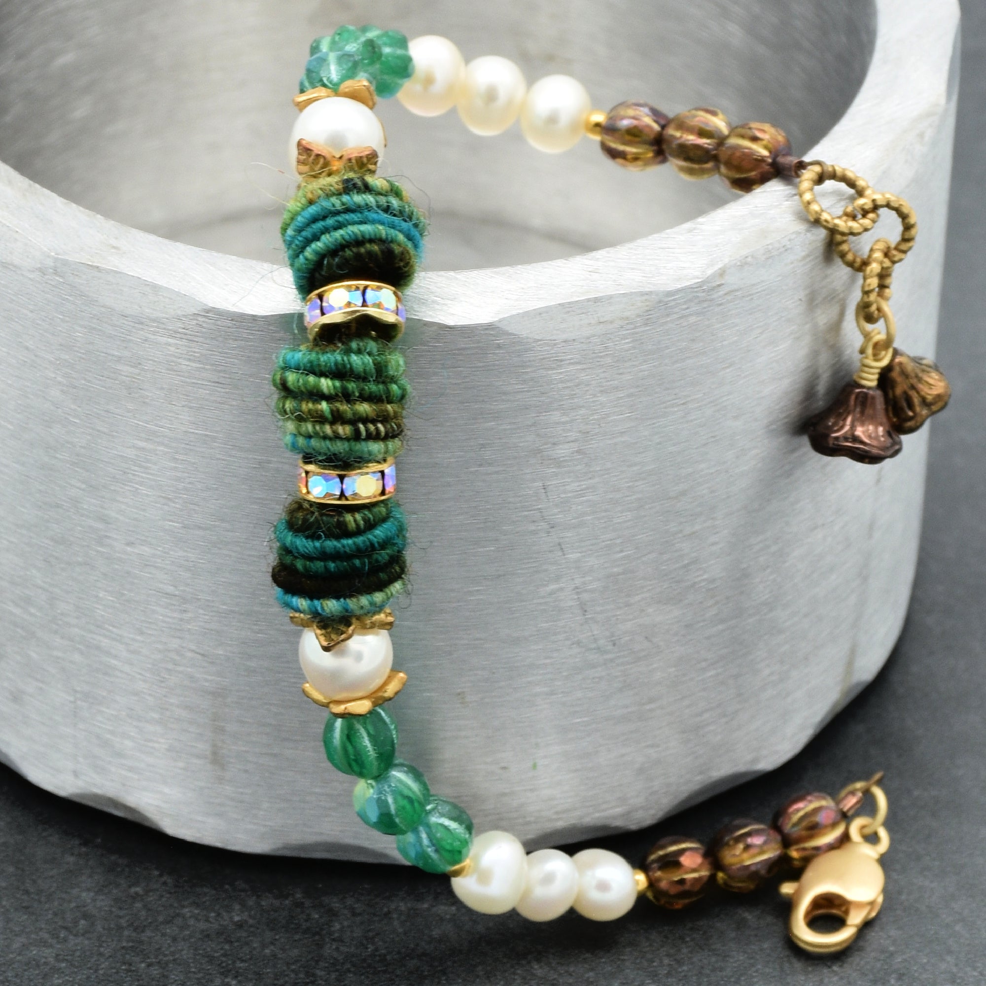 Beaded bracelet with green, white, and gold beads on a gray surface