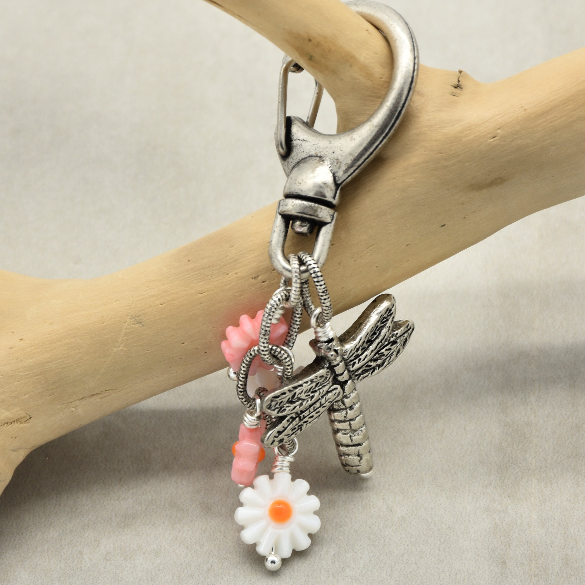 Keychain with floral and dragonfly charms on a wooden branch