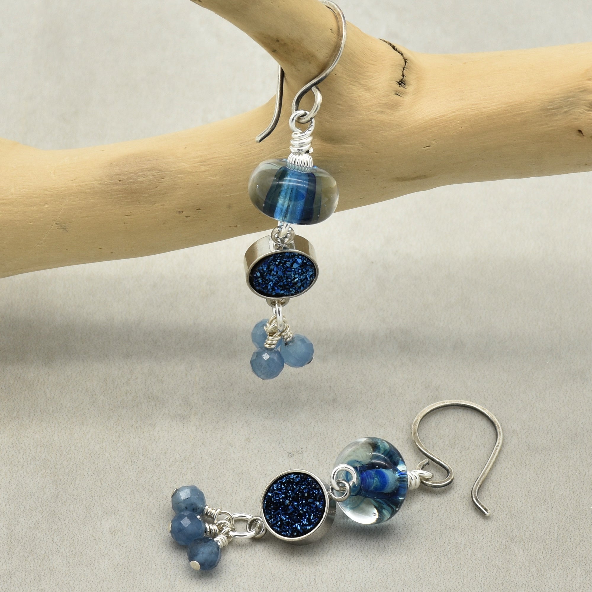 Blue beaded earrings with silver hooks on a light gray background