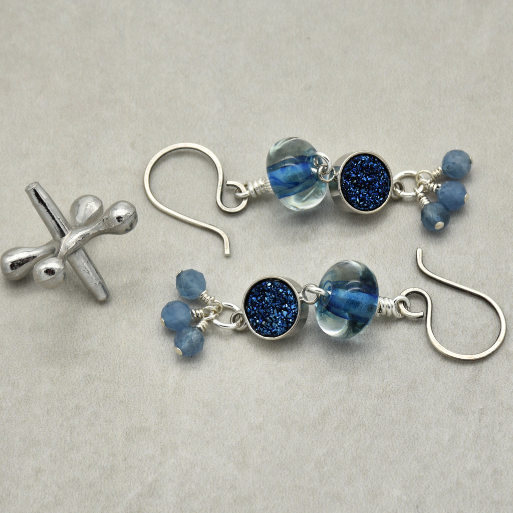 Pair of silver earrings with blue beads on a light gray background