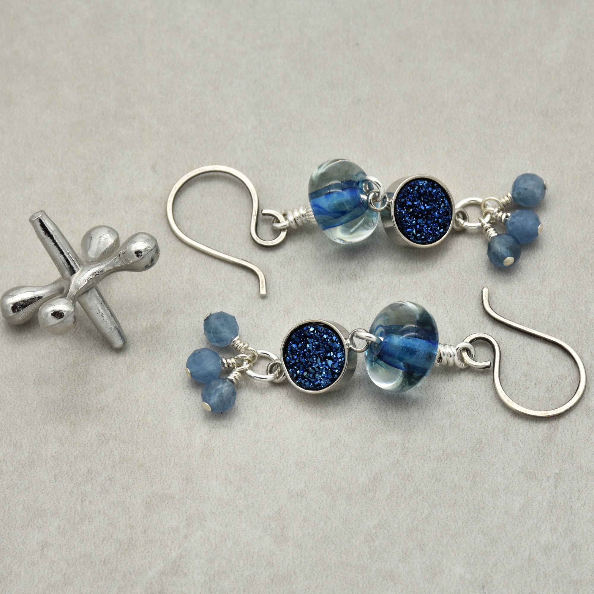 Pair of silver earrings with blue beads on a light gray background
