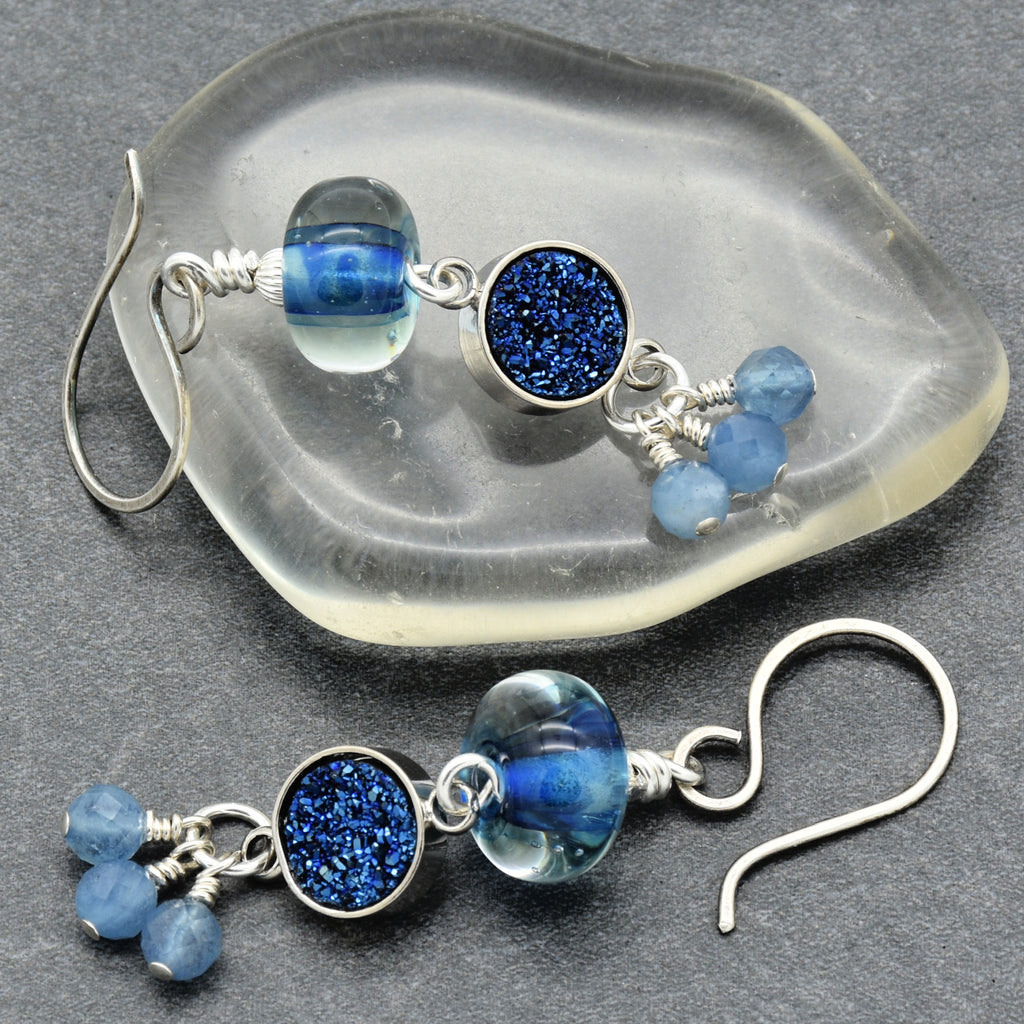 Pair of blue beaded earrings on a gray stone surface