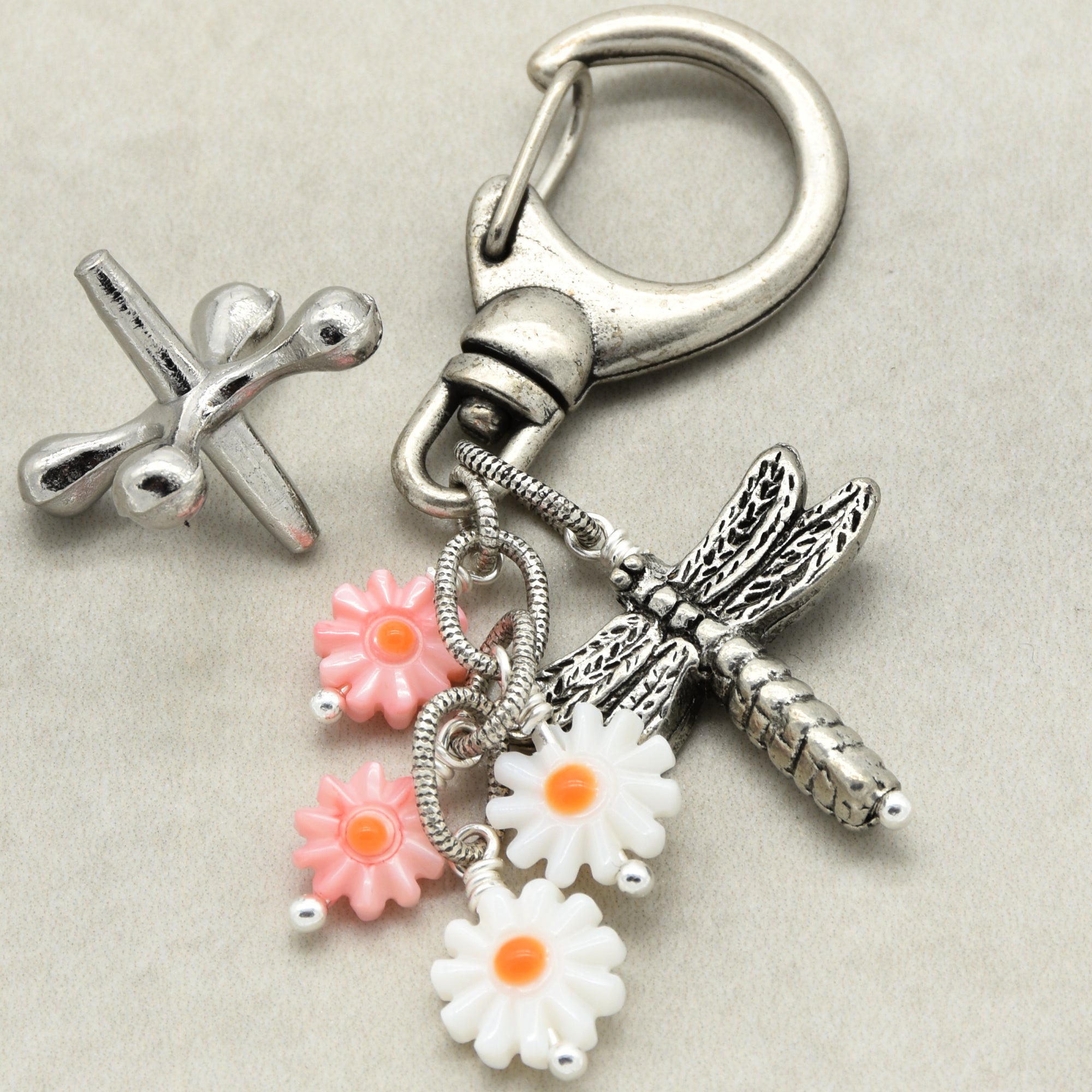 Keychain with dragonfly and flower charms on a light gray background