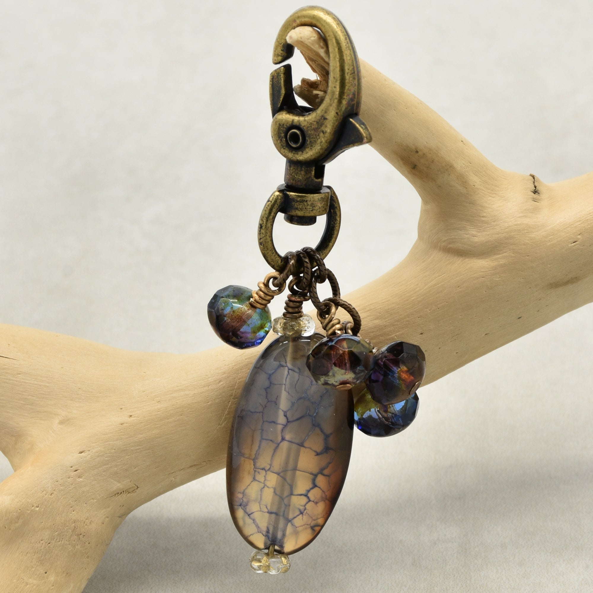Decorative keychain with stone pendant and beads on a wooden branch
