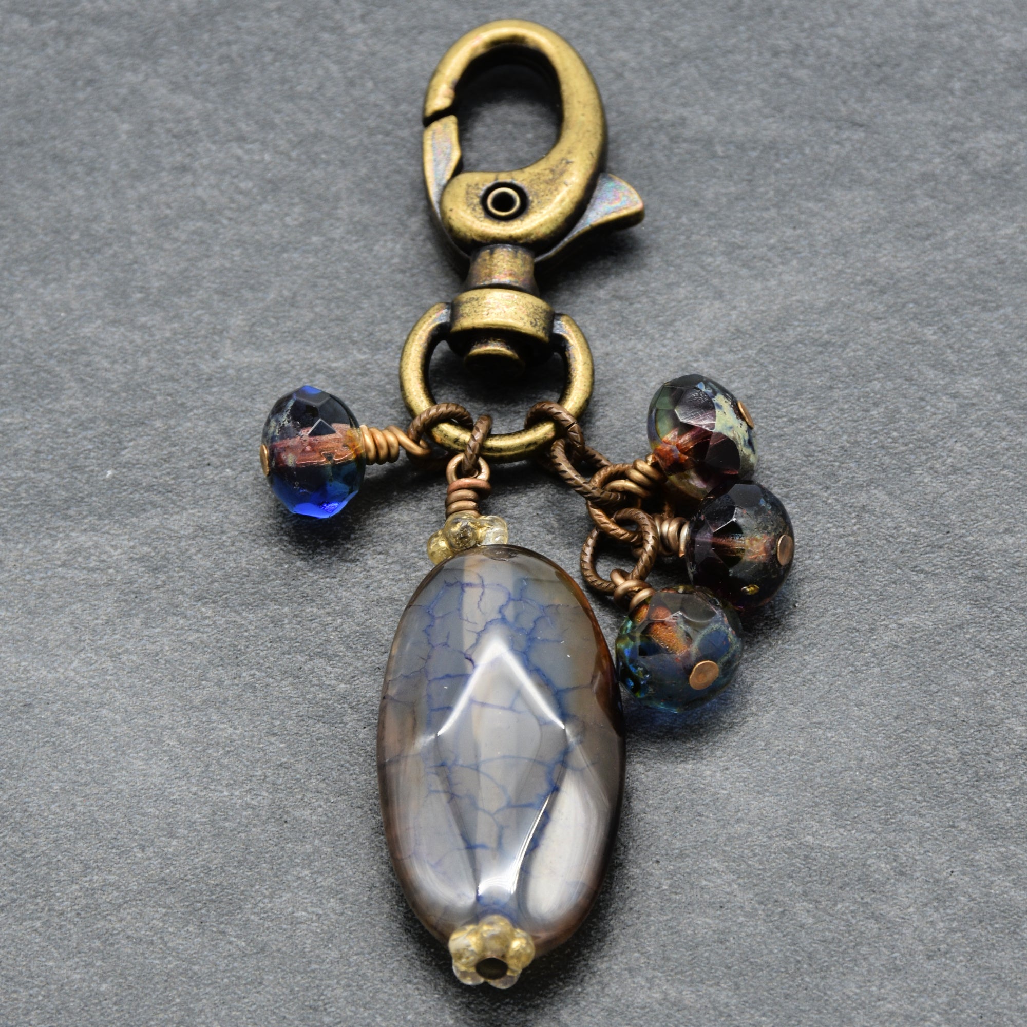 Decorative keychain with beads and a large stone on a gray background