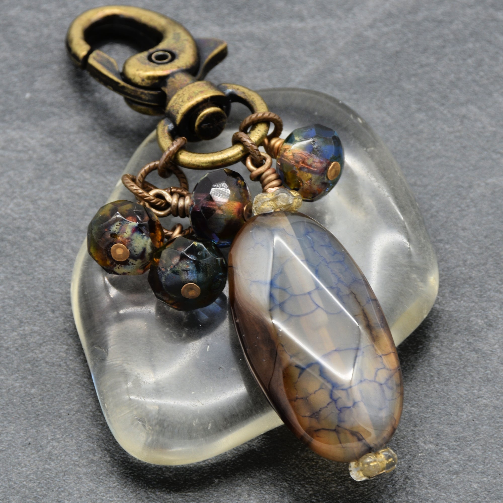 Jewelry keychain with beads and a large stone on a gray background