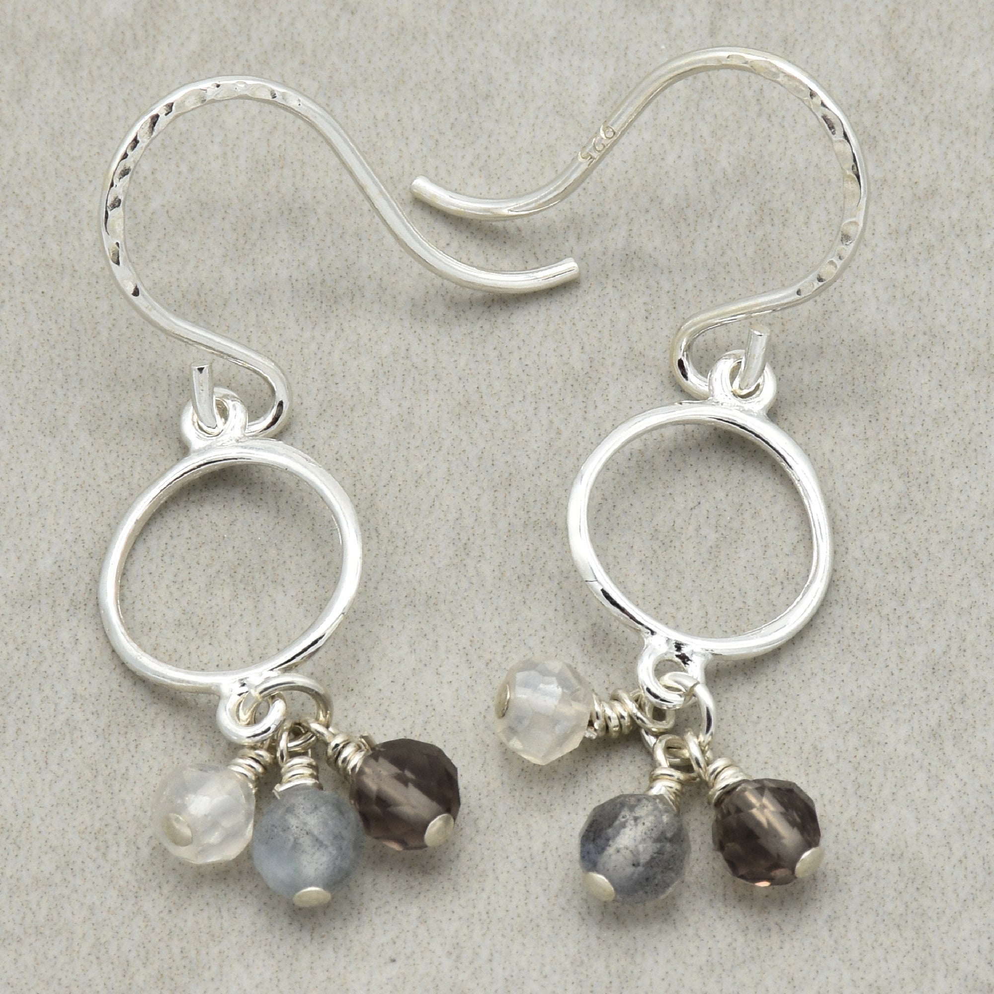 Silver earrings with small beads on a gray background