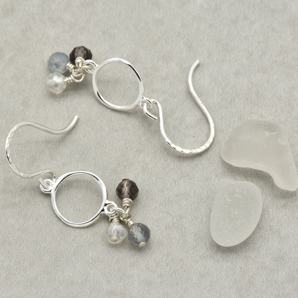 Silver earrings with beads on a gray surface