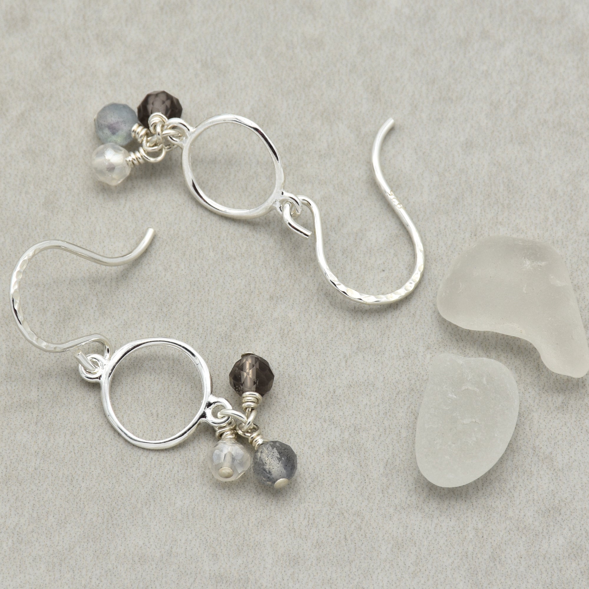 Silver earrings with beads on a gray surface