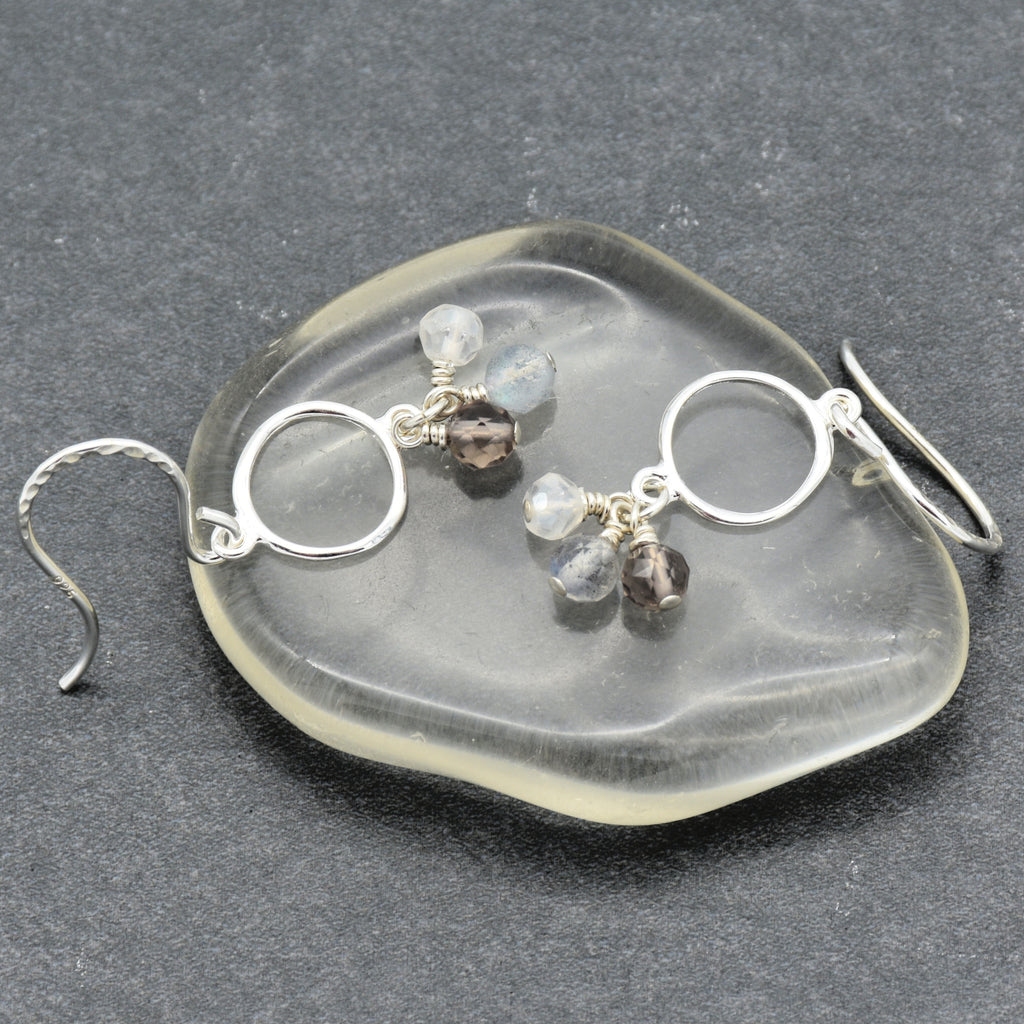 Silver earrings with gemstones on a clear stone surface
