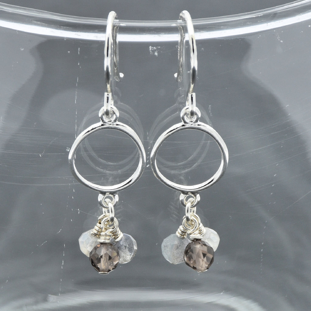 Silver earrings with circular designs and small beads on a clear background