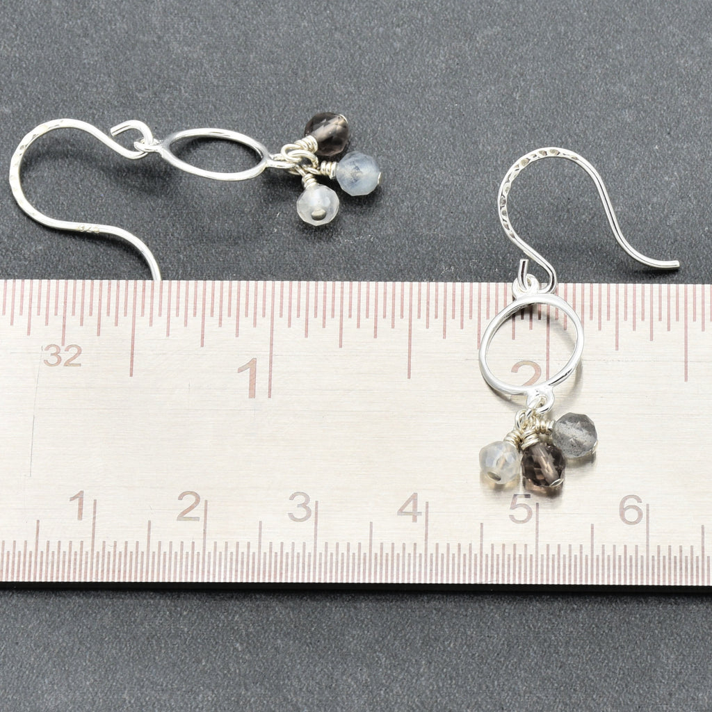 Silver earrings with gemstones on a ruler for scale