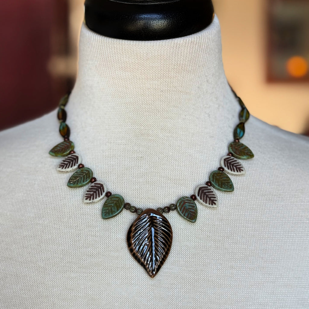 Leaf-shaped necklace on a mannequin bust with a blurred background