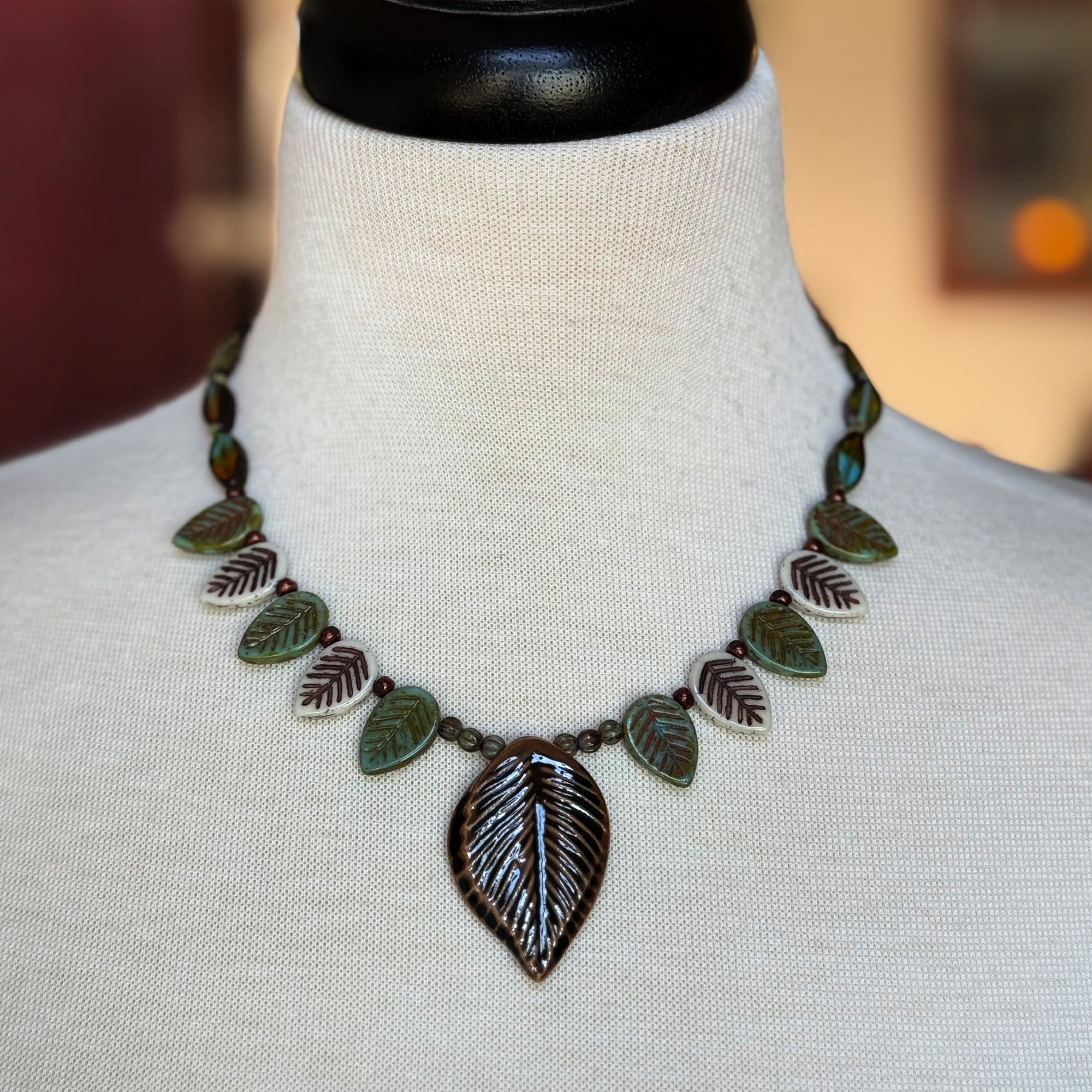 Leaf-shaped necklace on a mannequin bust with a blurred background