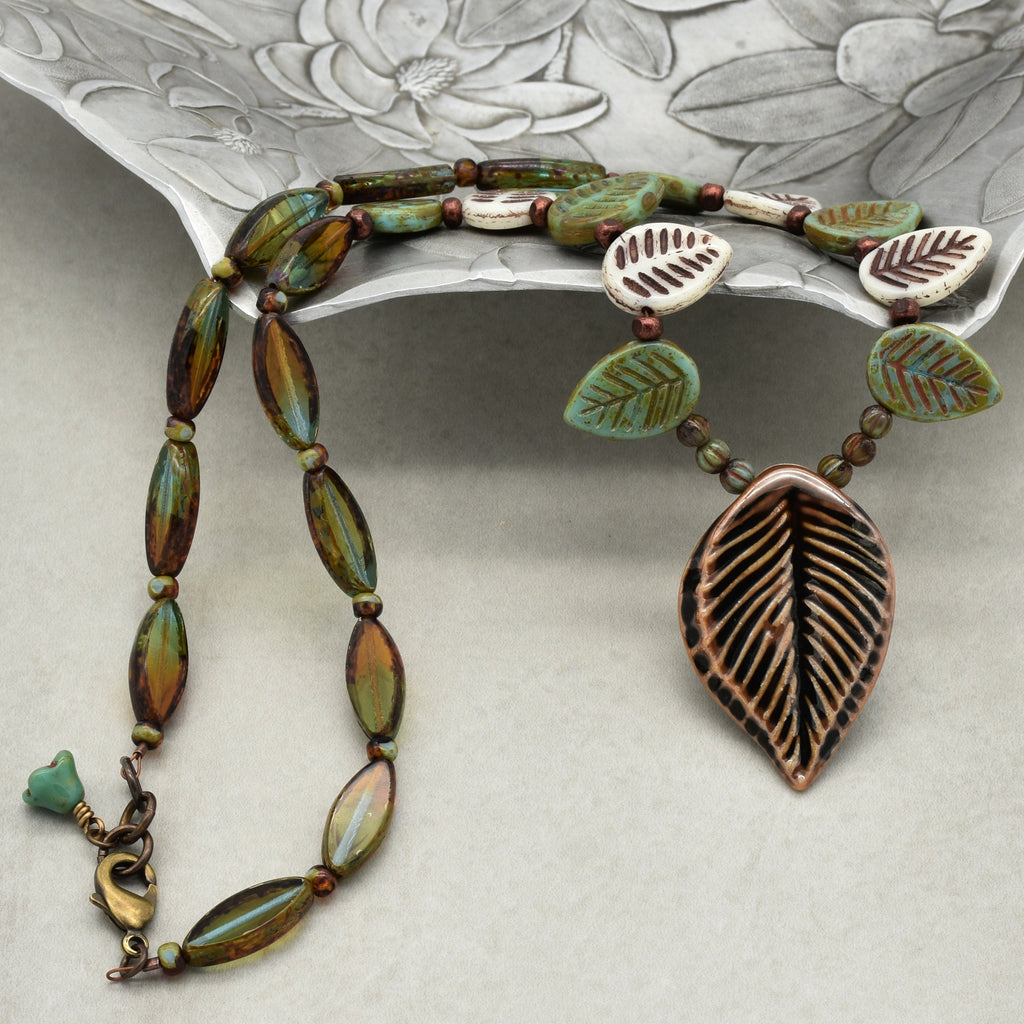 Necklace with leaf-shaped pendant on a textured surface