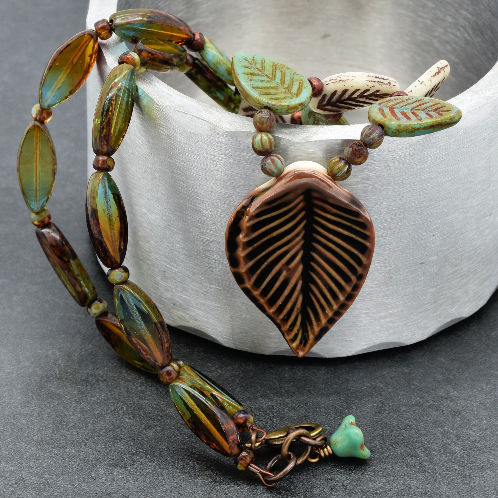 Brown and blue necklace with leaf-shaped beads on a gray background