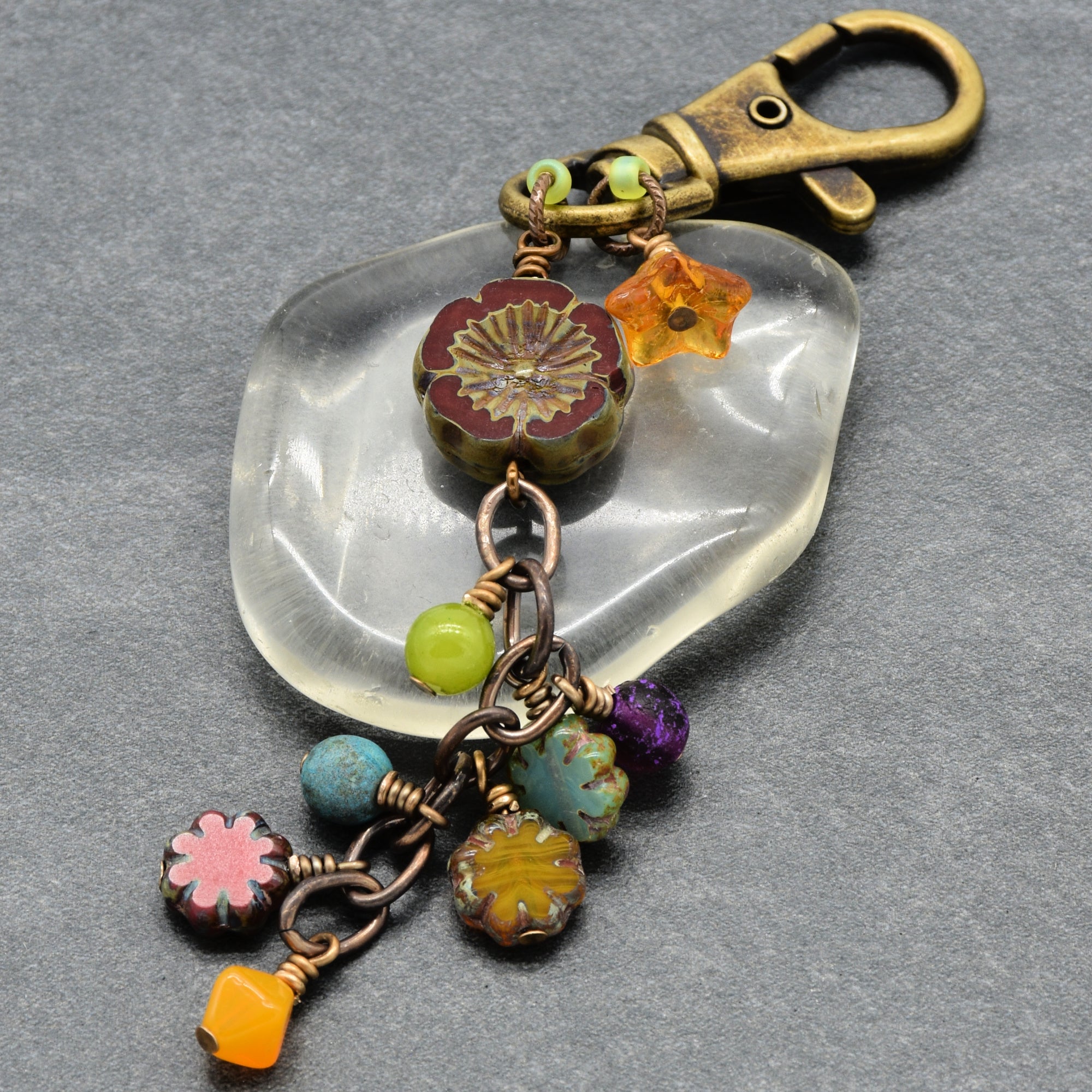 Colorful beaded keychain on a clear stone set on a gray background